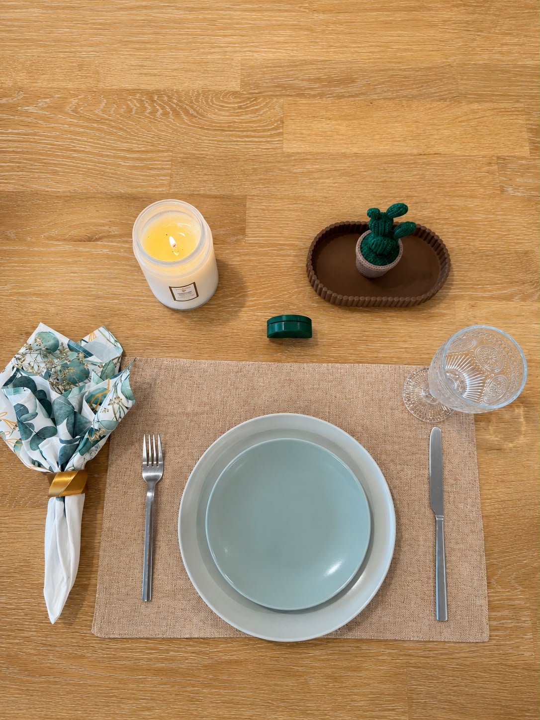 Eucalyptus Groove table setting with eucalyptus print napkin, gold napkin ring, and sand placemat