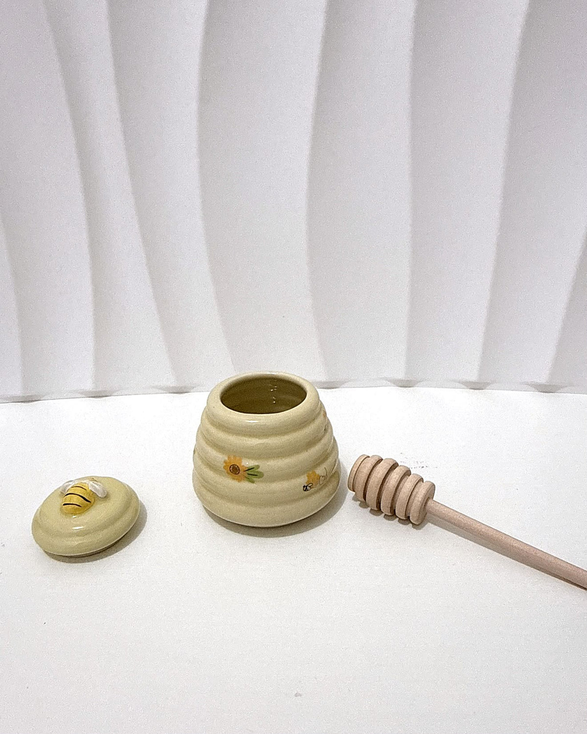 Honey pot open with lid and wooden dipper beside it