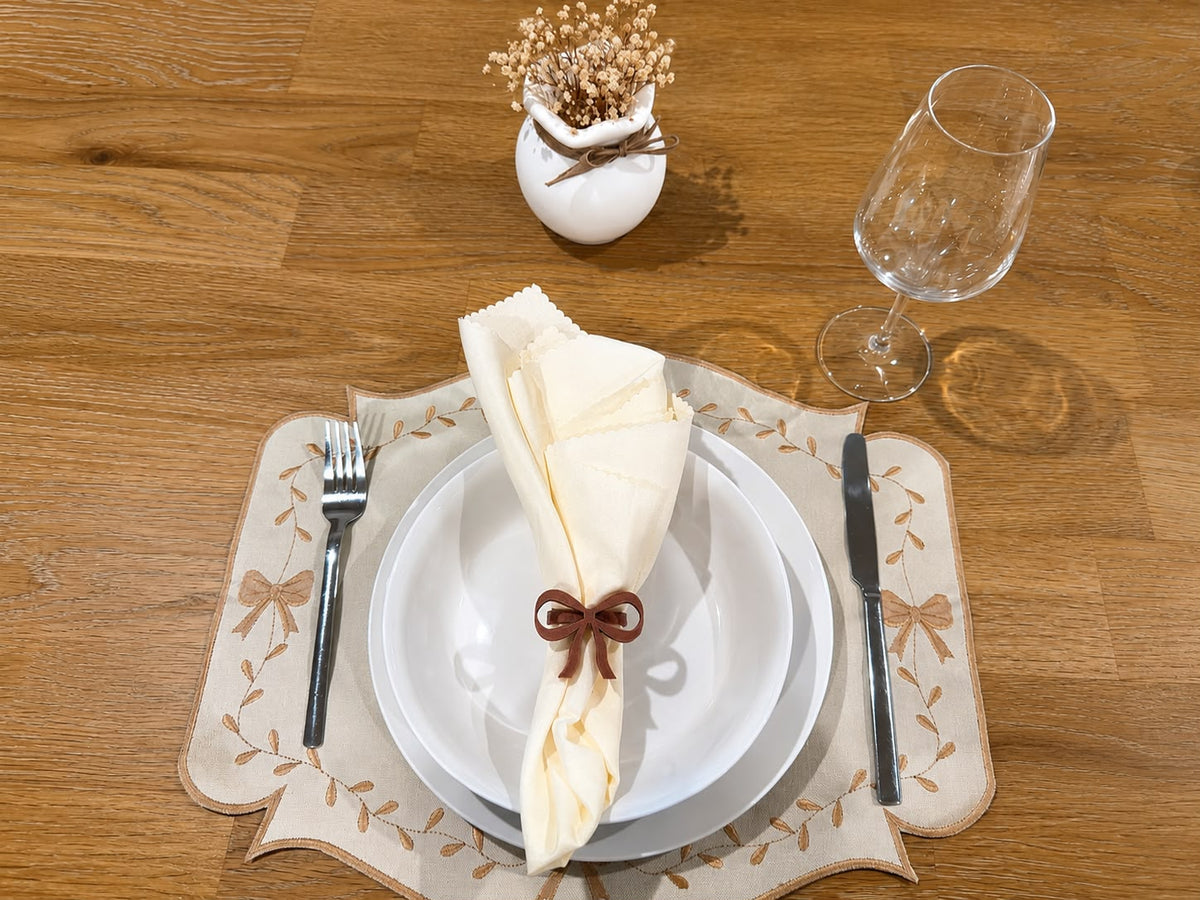 Ivory Grace table setting with cream napkin, aged-rose napkin ring, and beige embroidered placemat